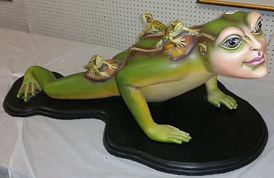 Ceramic frog with a human face and hands.