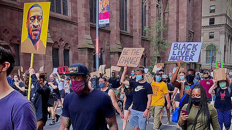 Demonstrators protesting police brutality carry posters, including Black Lives Matter.