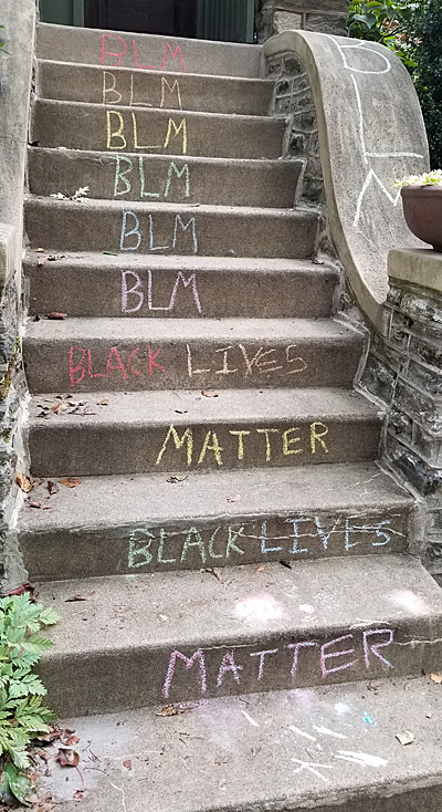 "Black Lives Matter" written in colored chalk on the concert steps of a home. 