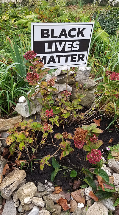 "Black Lives Matter" yard sign integrated into a flower garden. 