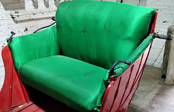 The colorful green seating in the one-horse open sleigh is ready for dashing. It appears to have been reupholstered in fabric. 