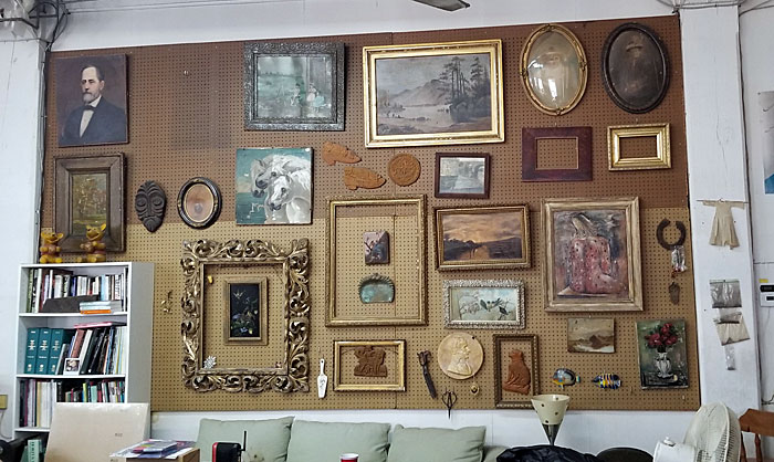 A wall of artwork and frames in Carole Abercauph's studio. She made the mask on the left when she was 10 years old.
