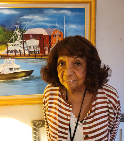 Bessie Ruth Bridges stands in front of her painting of a scene in Florida. "I passed this place. I went to see the lighthouse but the place inspired me more, so I ended up painting that one."